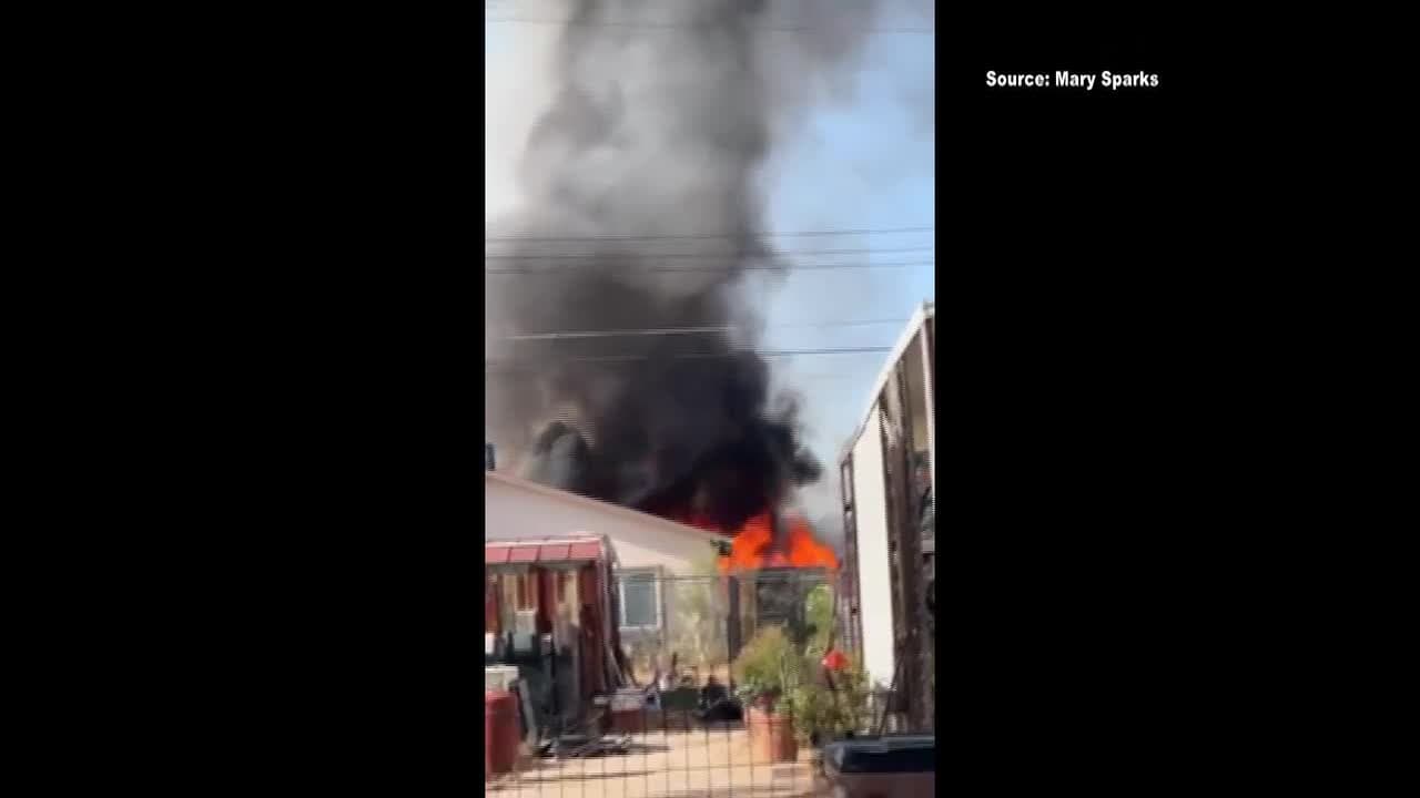 Viewer-shot video frame showing heavy black smoke and flames rising from an apartment unit during the early-morning Tucson fire.