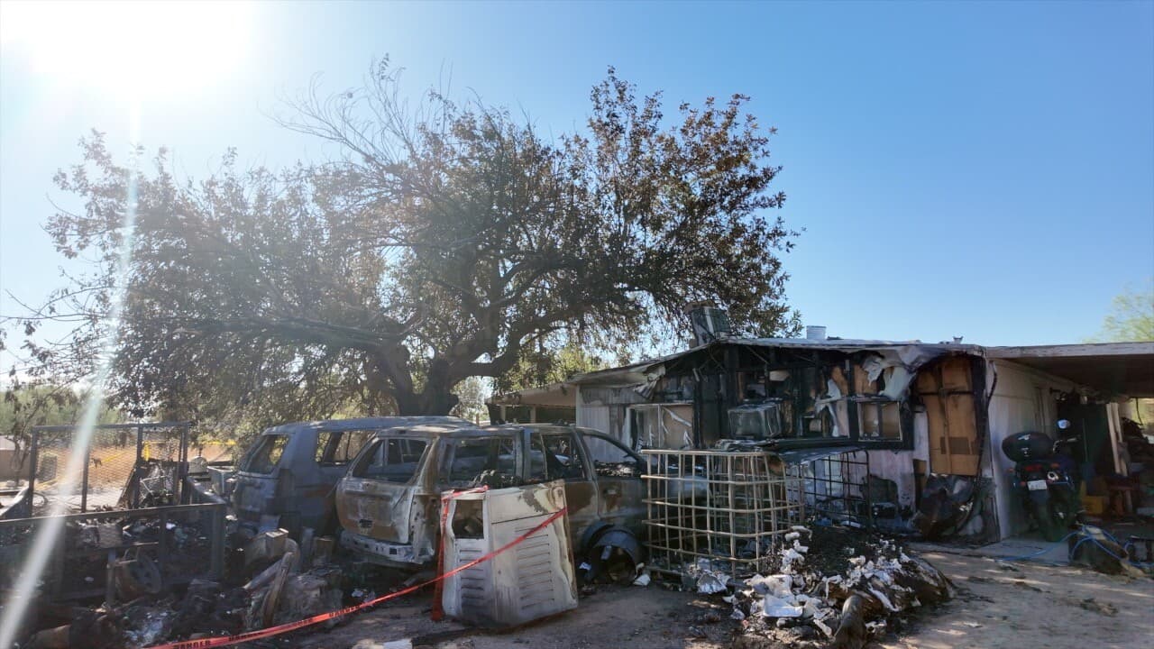 Burned vehicles and the charred exterior of a Mesa home after a blaze — body-camera footage shows officers rushing into the burning residence to try to rescue the couple inside.