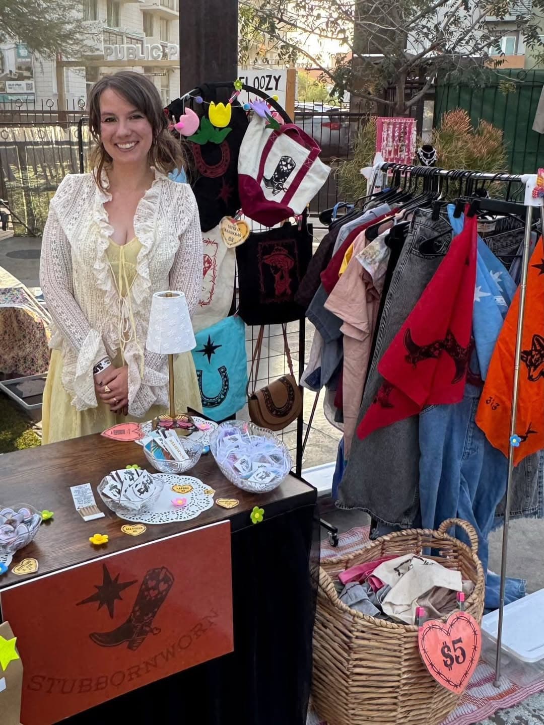 The artist featured in this story at a local market booth displaying upcycled clothing and handmade accessories for sale.