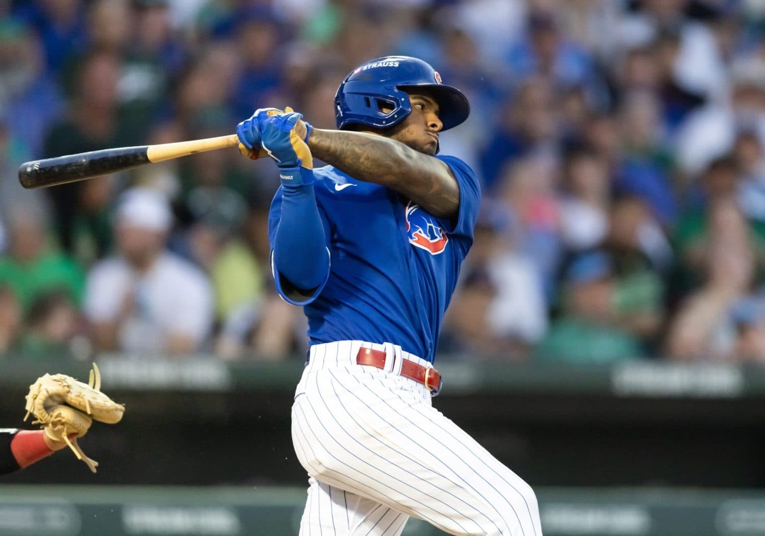 Cubs hitter follows through on a powerful swing at Wrigley Field; image suits the story about a young player pushing to secure a major-league roster spot amid infield competition.