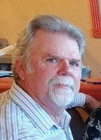 Portrait accompanying the obituary on azcentral.com — an older man with white hair and a trimmed beard pictured indoors.