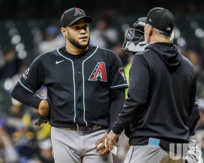 Arizona Diamondbacks pitcher speaks with a coach on the mound during the Brewers–Diamondbacks series opener at Chase Field.