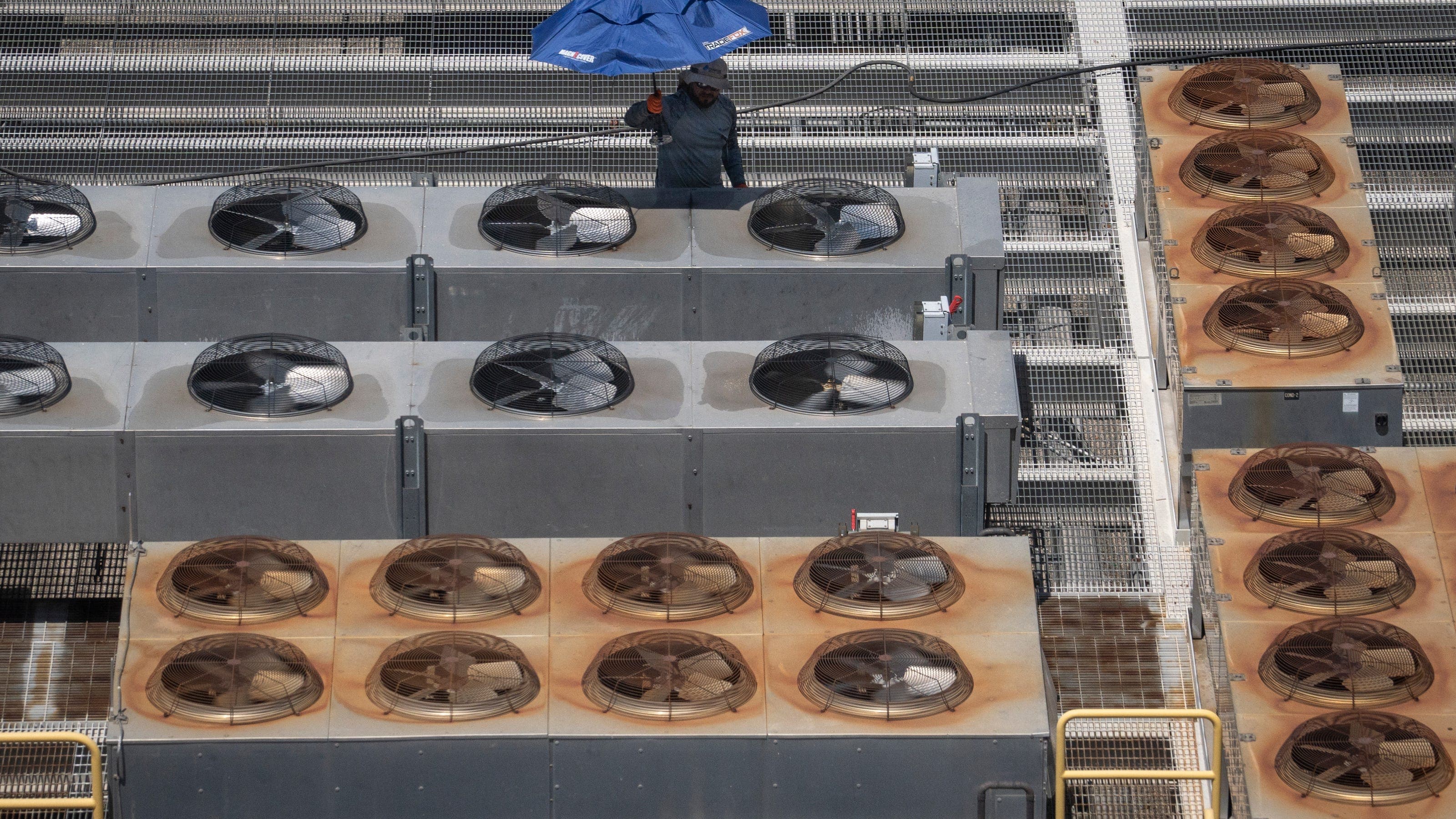 Rows of rooftop air-conditioning condensers and fans on a large building — a common sight in Phoenix that illustrates why many cooling systems are installed on roofs.