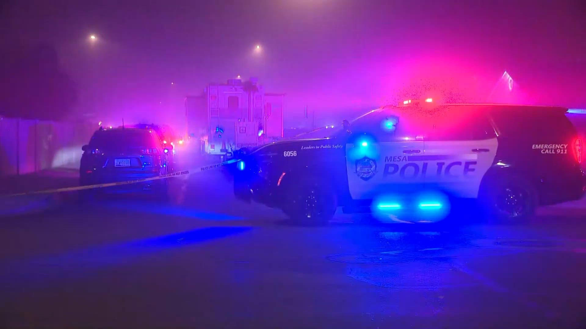 Mesa police patrol vehicle with flashing lights and crime‑scene tape blocks a neighborhood street after officers shot and killed a man accused of attacking his ex‑wife and children, Aug. 2026.
