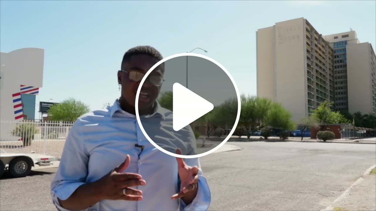 A reporter stands outside the Tucson House high‑rise, where tenants say asbestos‑laden dust from ongoing renovations has made them feel unsafe and sick.