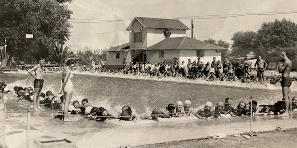 Historic photograph of swimmers and a large crowd at an early Arizona municipal pool, illustrating community gatherings at the state's long-standing public pools.
