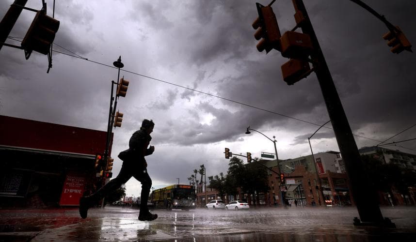 A pedestrian sprints through heavy rain beneath dark monsoon clouds in Tucson as the storm swept the city, contributing to widespread flooding and power outages.