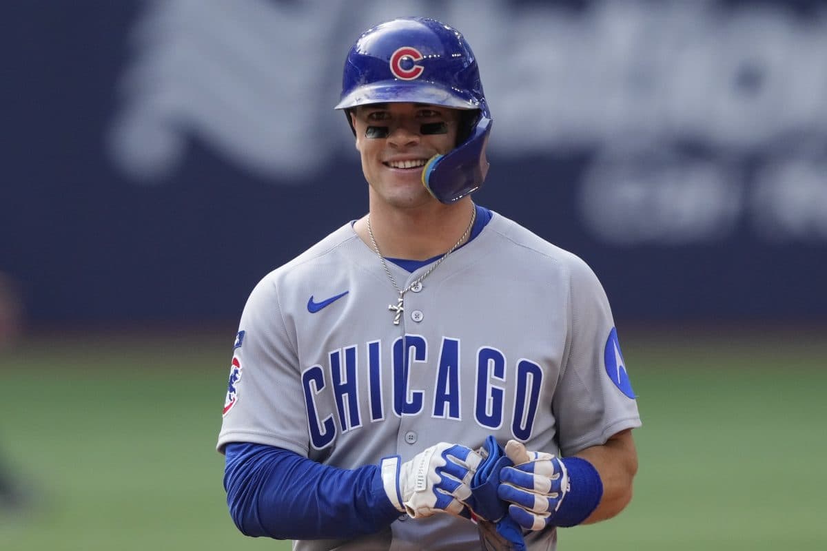 Chicago player in the road greys smiles on base during a game; a good visual for the article’s discussion of roster battles and how on-field performance can affect playing time.