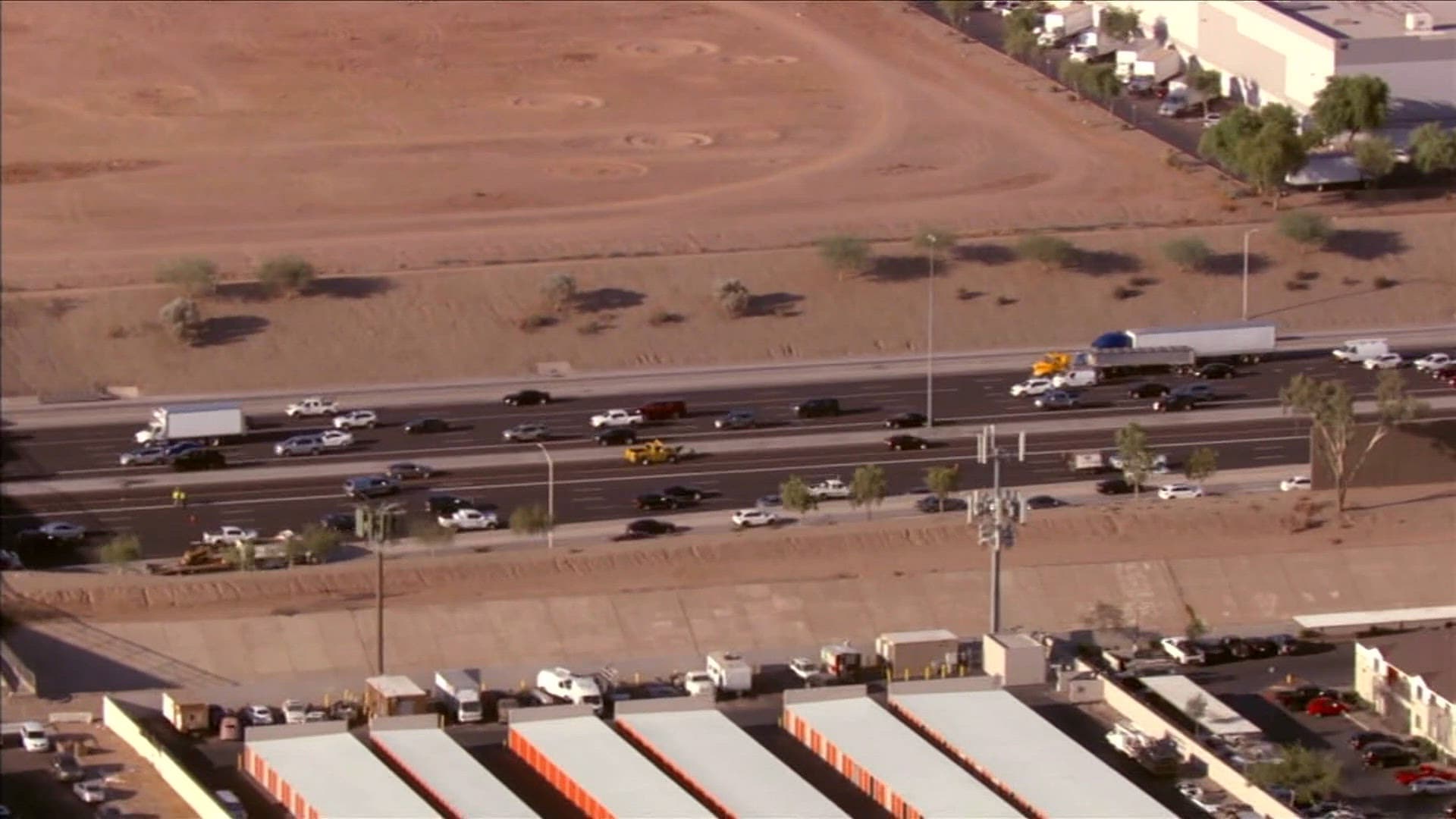 Aerial shot of multi‑lane freeway traffic and service vehicles near an industrial area — drivers should expect delays during the planned July 10–13 weekend closures.