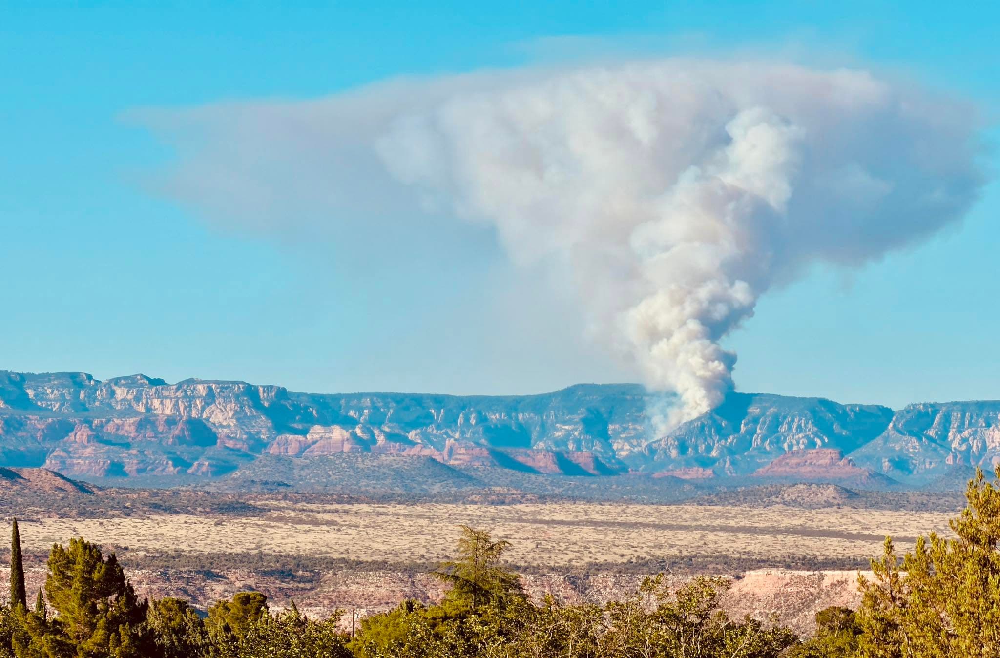 Thick column of smoke from the Pocket Fire rises above red-rock cliffs north of Sedona as crews respond to the blaze that forced evacuations in Oak Creek Canyon.