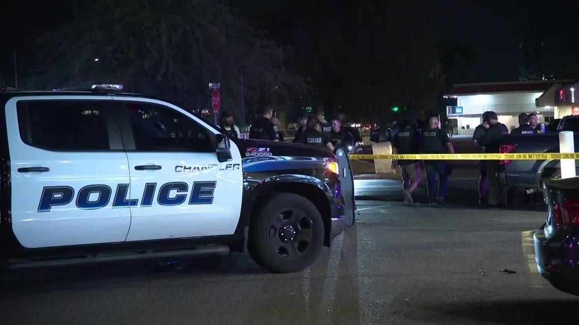 A Chandler police vehicle and officers at the cordoned-off parking lot where investigators responded to the Tempe incident in which a suspect was killed while fleeing.