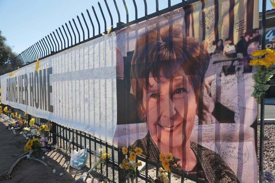 A large memorial banner bearing a woman’s photograph, handwritten messages and flowers attached to a fence outside a neighborhood, displayed amid the FBI probe into ransom-note claims in the missing-person case.
