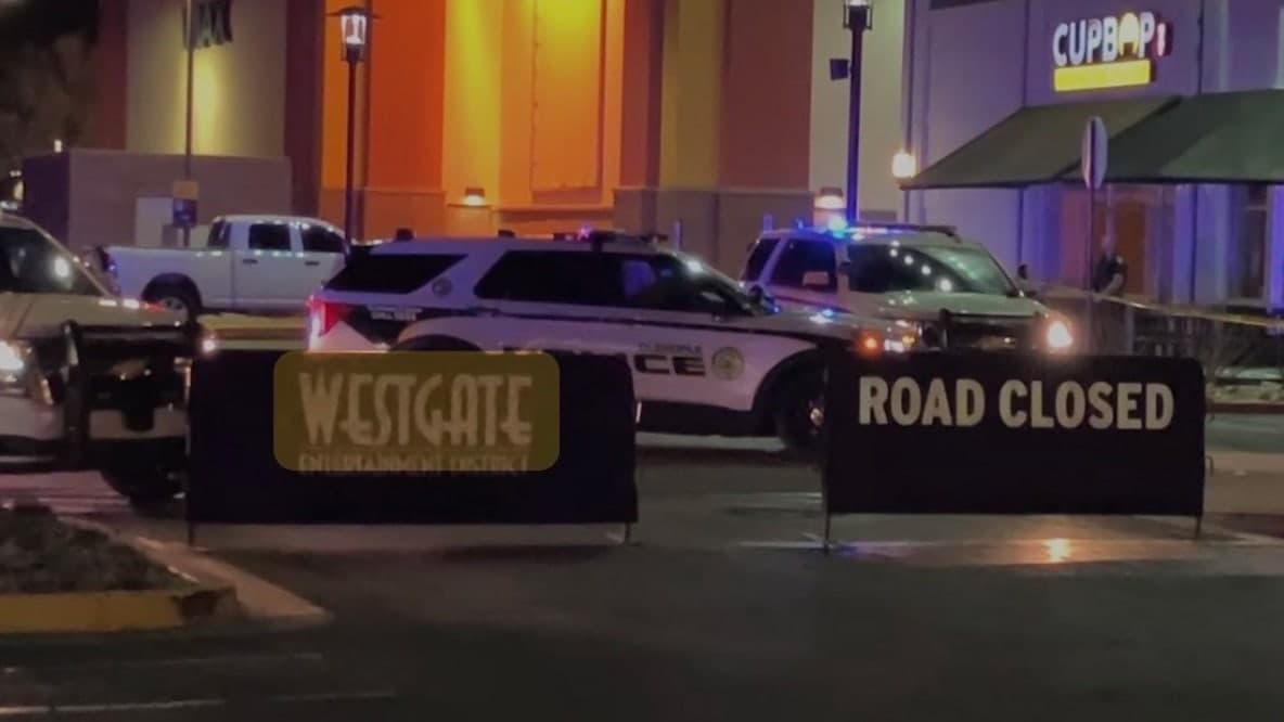 Glendale police SUVs and 'Road Closed' barricades at the scene outside a Westgate entrance as officers respond to an incident; authorities say a driver accidentally shot himself behind the wheel.