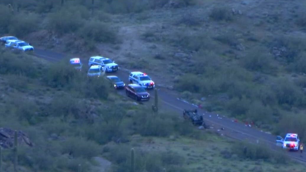 An overturned vehicle lies on its roof with multiple emergency units at the scene of the rollover; authorities say a 51-year-old woman died in the early-morning crash.