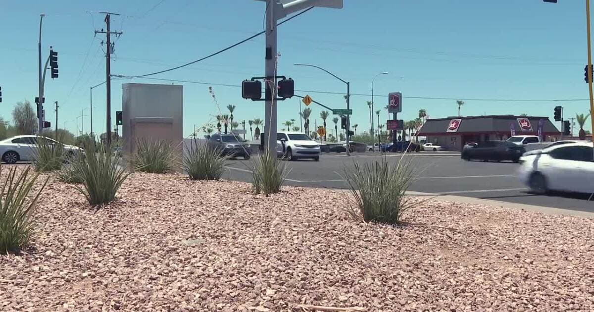 The Mesa intersection where police say a two‑vehicle, red‑light crash occurred; traffic lights and nearby businesses are visible at the scene.