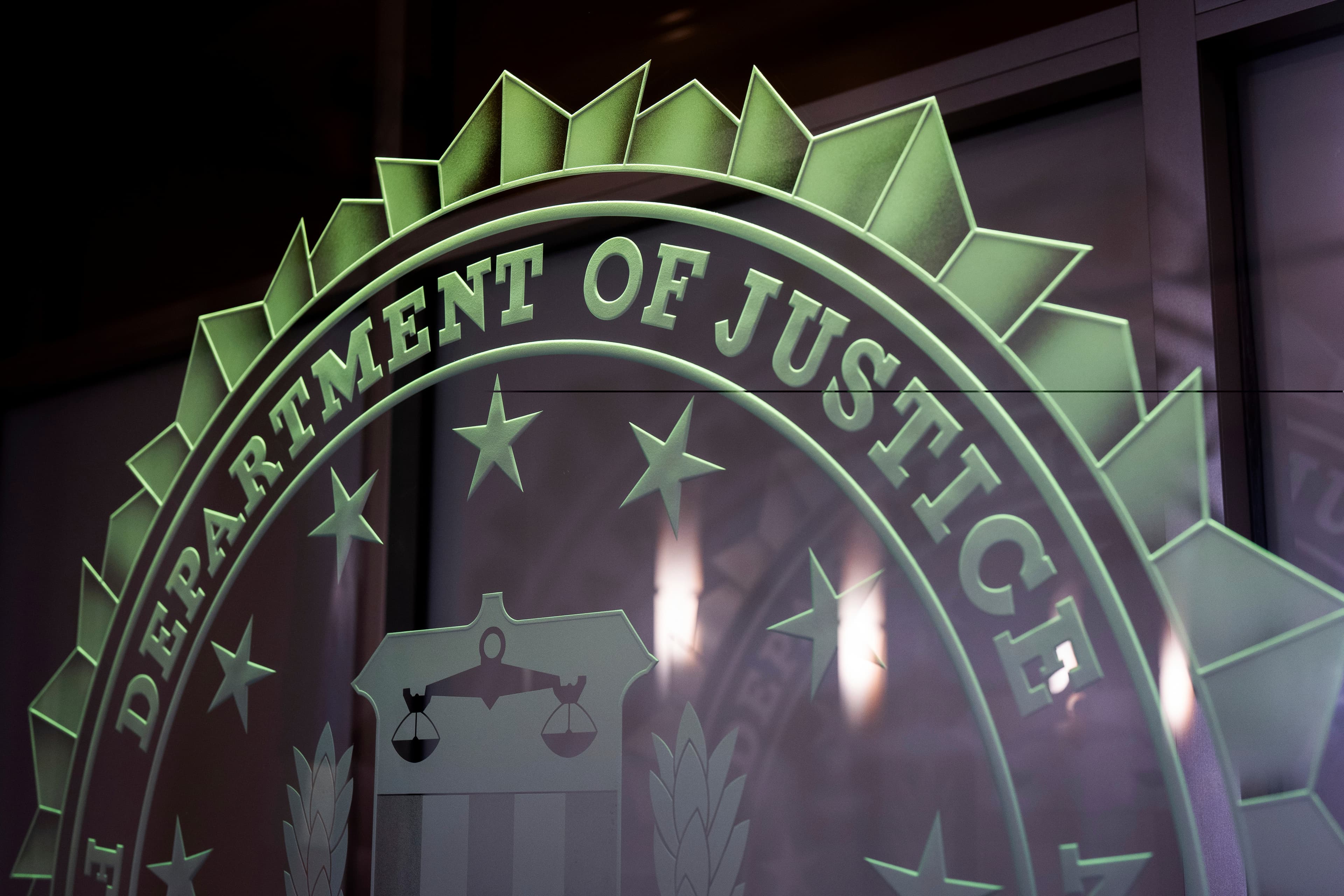Department of Justice emblem on glass at a federal building — used to illustrate the FBI/DOJ involvement in the wire-fraud probe of the Mesa tech startup.
