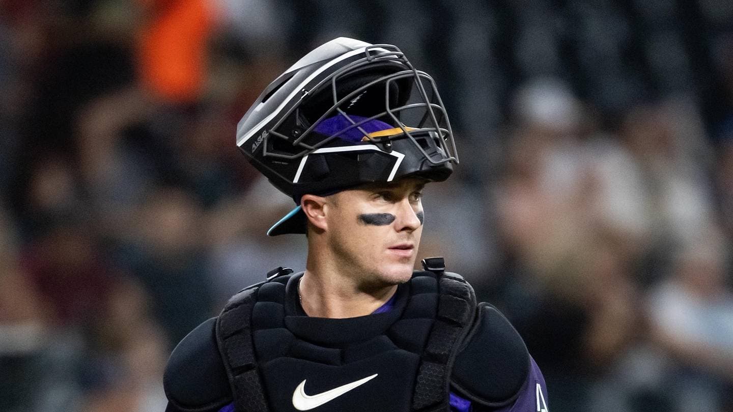 McCann in full catching gear with mask atop his helmet during a game, underscoring his defensive presence as he rejoins Arizona's catcher group.