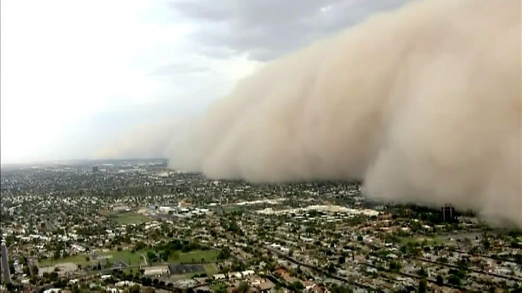 A massive dust wall pushes over Phoenix neighborhoods, dramatically reducing visibility as the storm drives air pollution to hazardous levels across the Valley.
