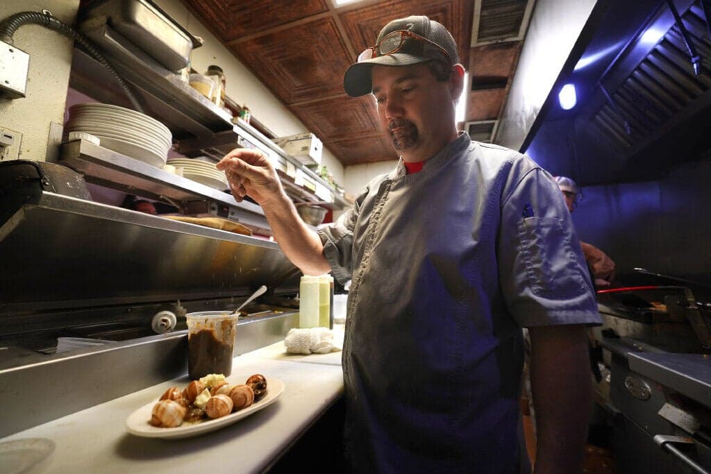 A chef at Dante's seasons a dish in the restaurant's kitchen; Dante's is set to close later this month after 13 years.