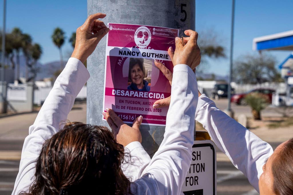 Volunteers post a missing-person flyer on a street pole in Tucson, Ariz., as part of ongoing efforts after a February disappearance.