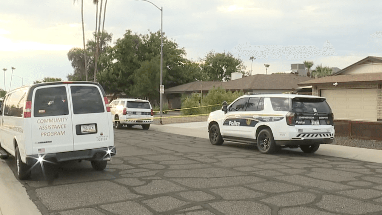 Phoenix police SUVs and a Community Assistance Program van parked near a residence at 28th Street and Shea Boulevard as officers tape off the scene during an early-morning fatal shooting investigation.