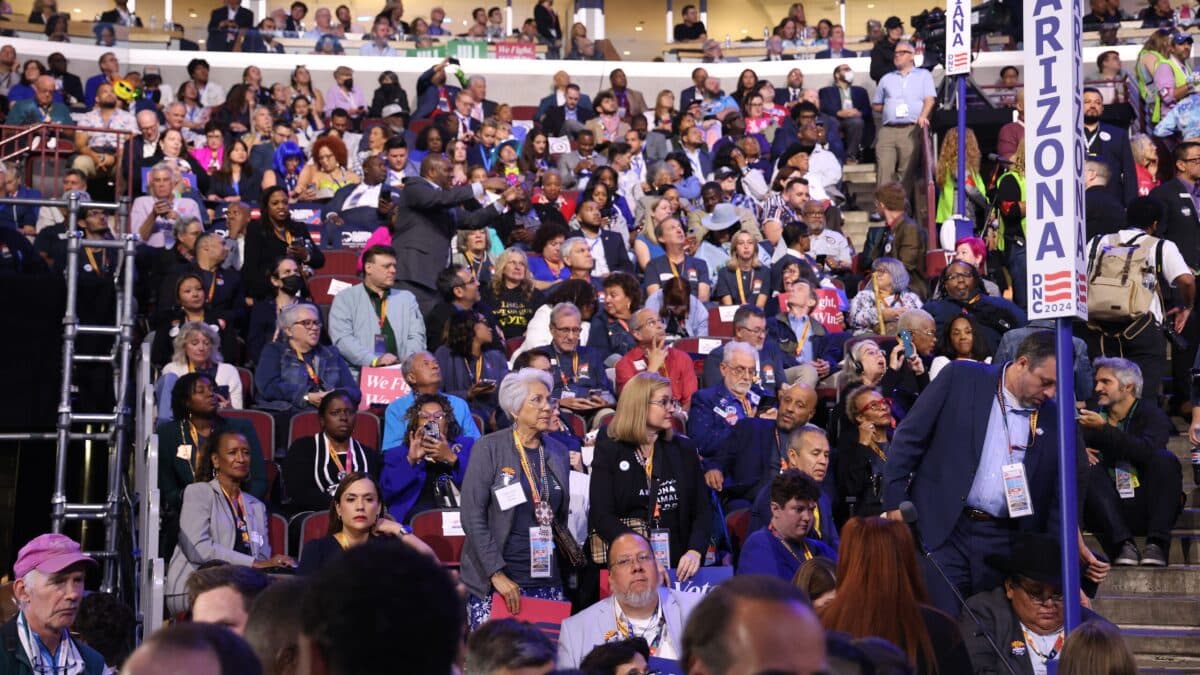 Delegates and attendees packed into the convention arena next to an 'Arizona' marker, the sort of party gathering the Tucson teacher covers for his classroom reports.