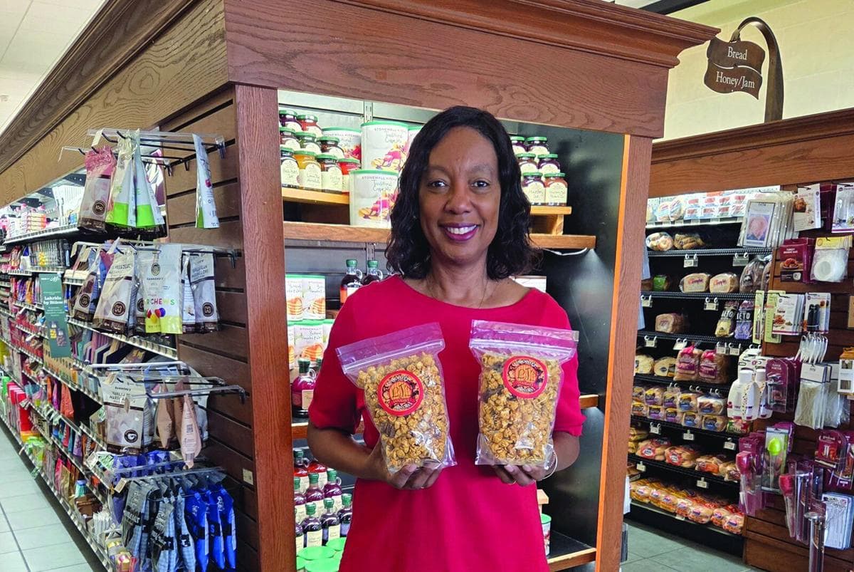 Mesa entrepreneur showcases two bags of her gourmet popcorn at a local market, part of her pop‑up gourmet business.
