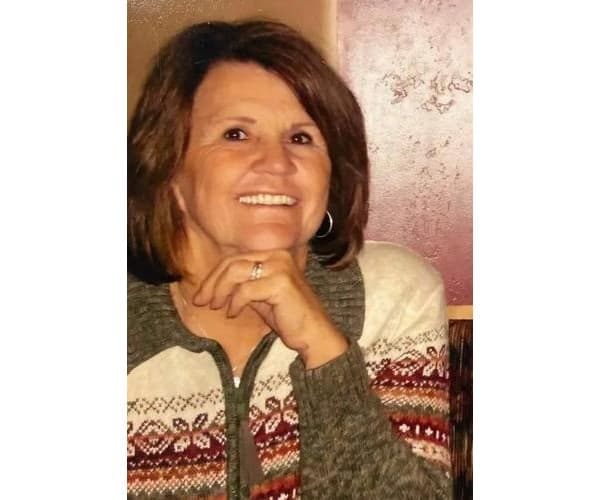 Portrait published with the obituary, showing a smiling woman in a patterned sweater.