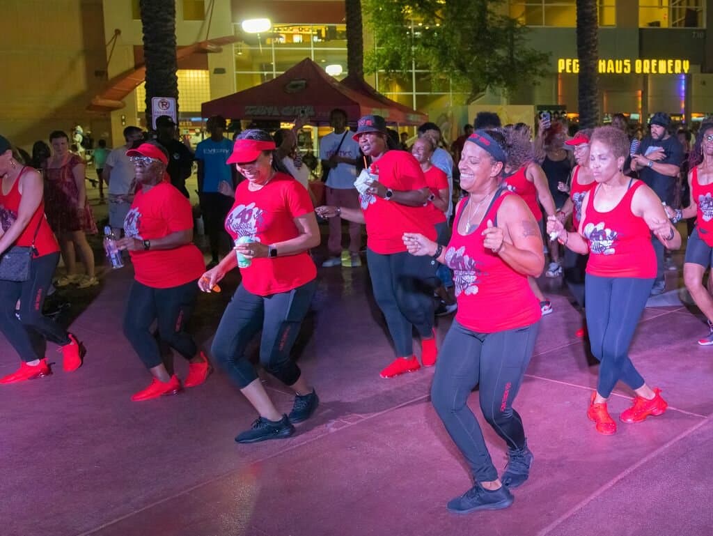 A group of dancers in matching red shirts performs at a nighttime Juneteenth celebration in Tempe, part of community events to raise awareness about the holiday.
