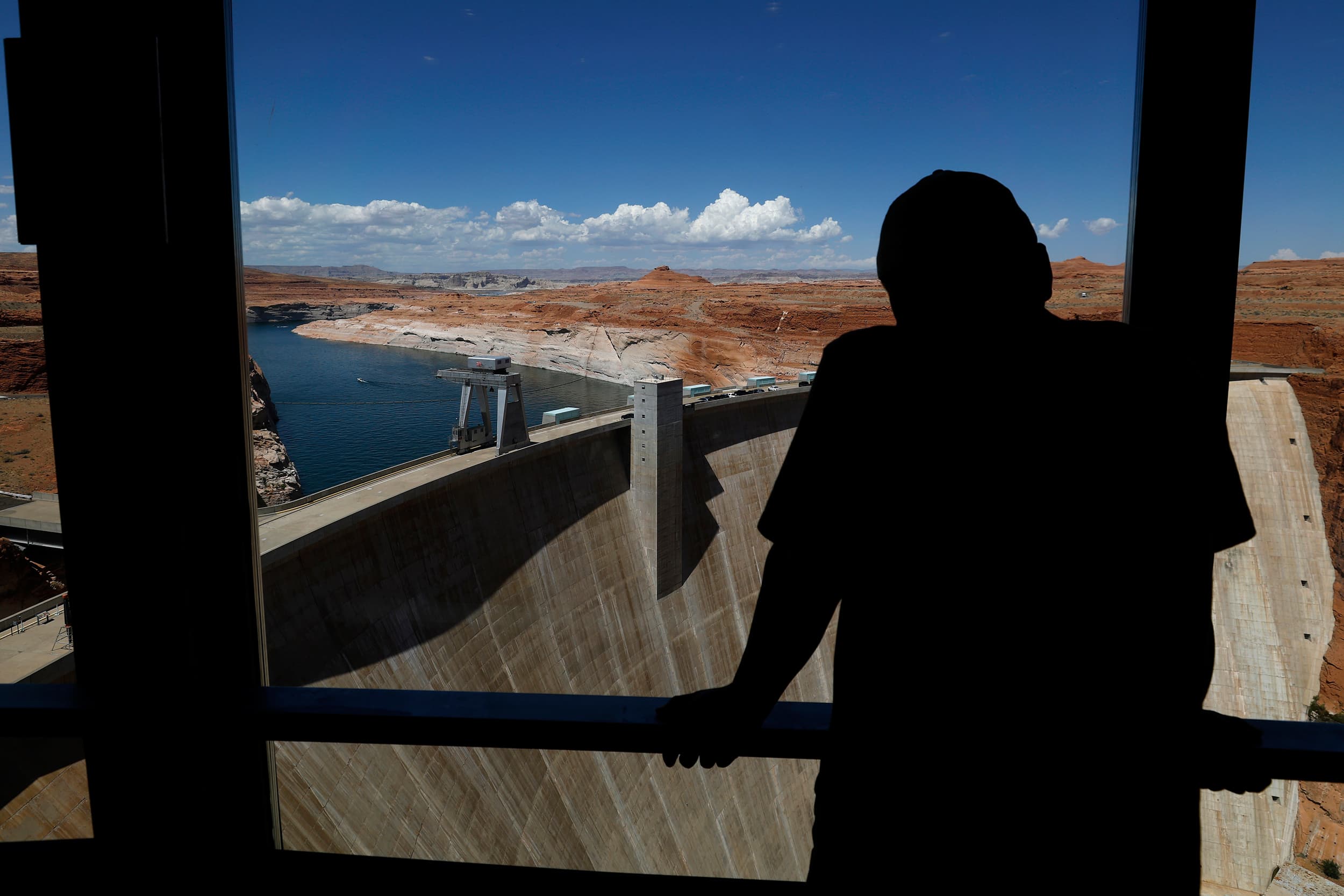 Silhouette of a visitor overlooking a large Arizona dam and reservoir, highlighting water-resource infrastructure as the state lags peers on environmental metrics.