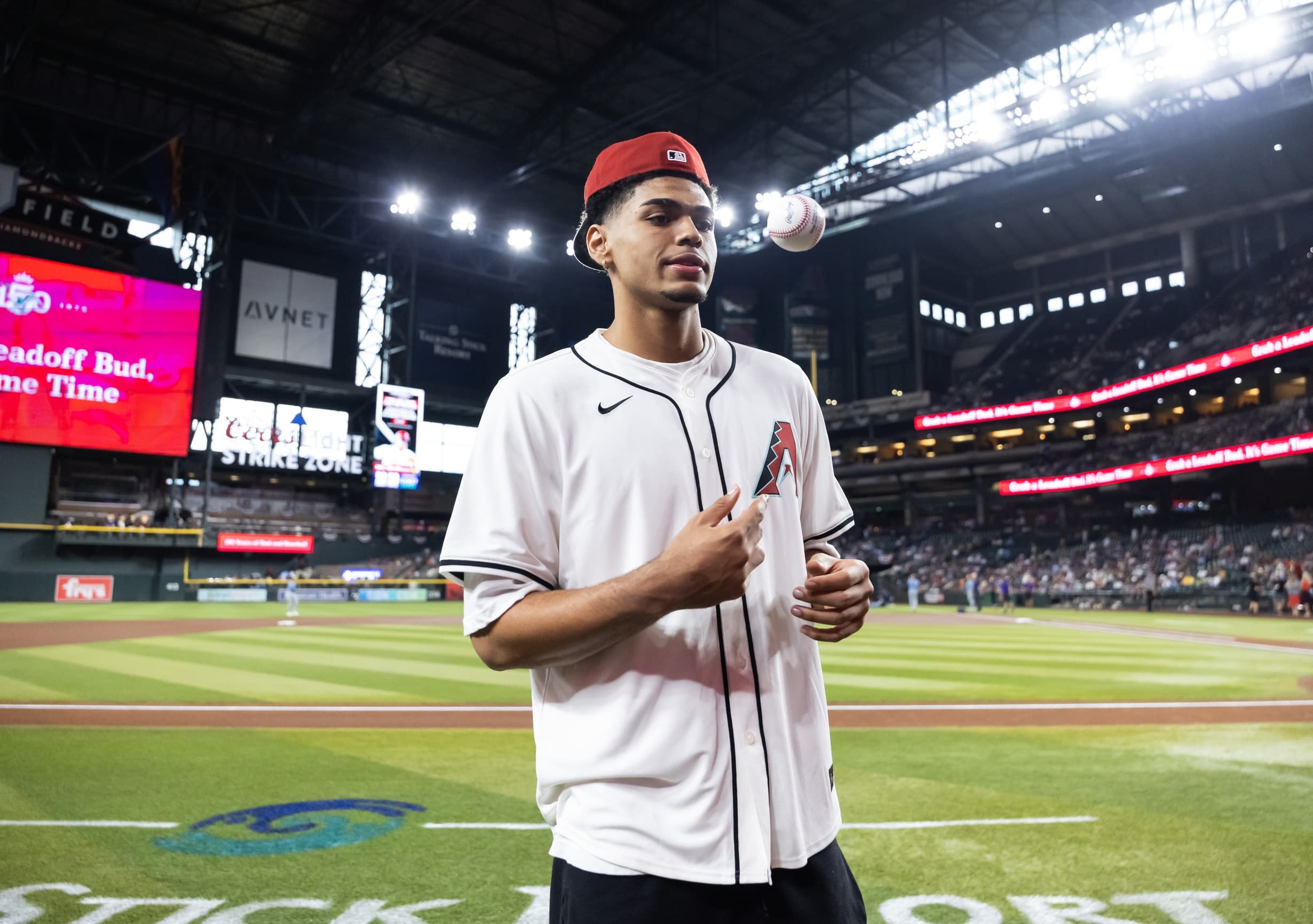 Phoenix Suns rookie Koa Peat at Chase Field with the ceremonial first pitch in midair during the Diamondbacks game.