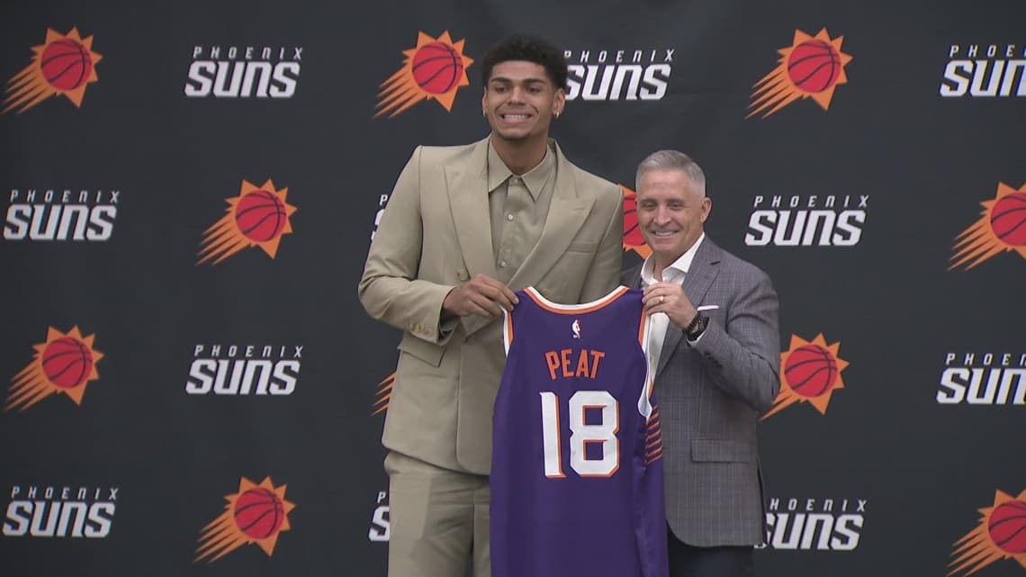Phoenix Suns first-round draft pick holds a No. 18 Suns jersey alongside team officials at a press conference in Phoenix.