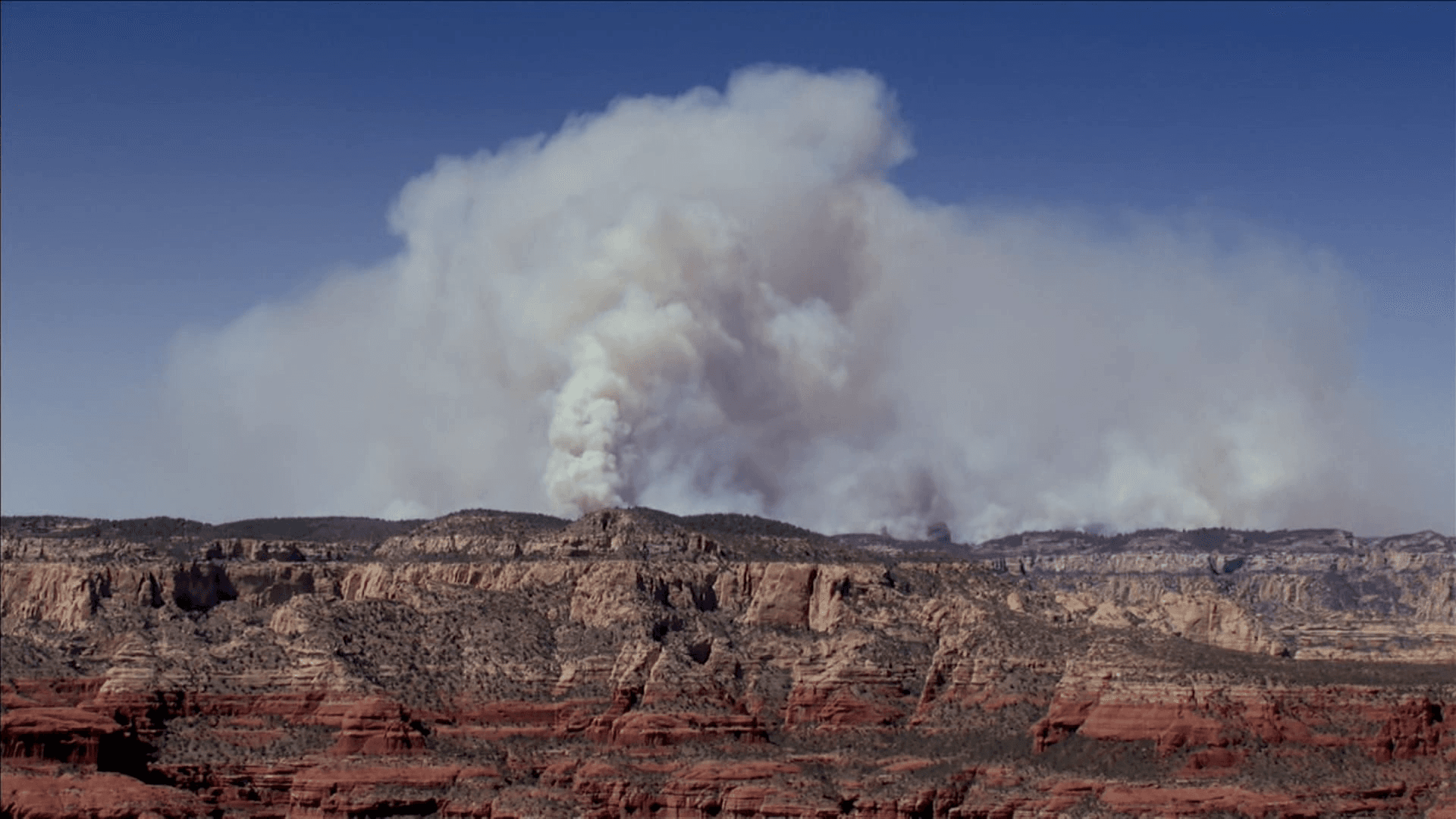 A large smoke plume rises over red‑rock terrain near Sedona from the Pocket Fire, one of the wildfires crews are working to contain as officials stage resources statewide.
