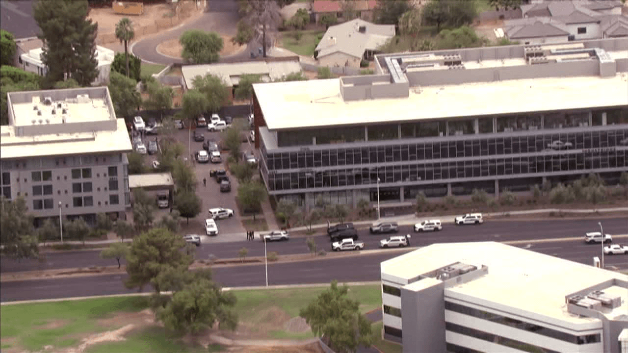 Aerial view of office buildings and parked police vehicles along a street in central Phoenix as authorities respond to a DPS detective-involved shooting.
