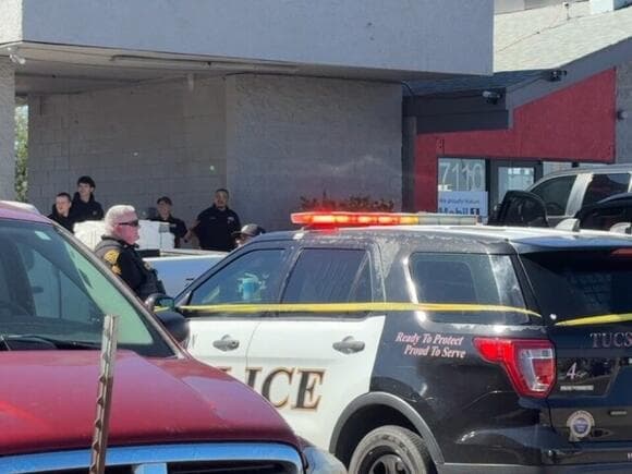 Tucson Police SUV and yellow crime-scene tape outside a storefront near the east-side intersection where the March road‑rage shooting occurred.