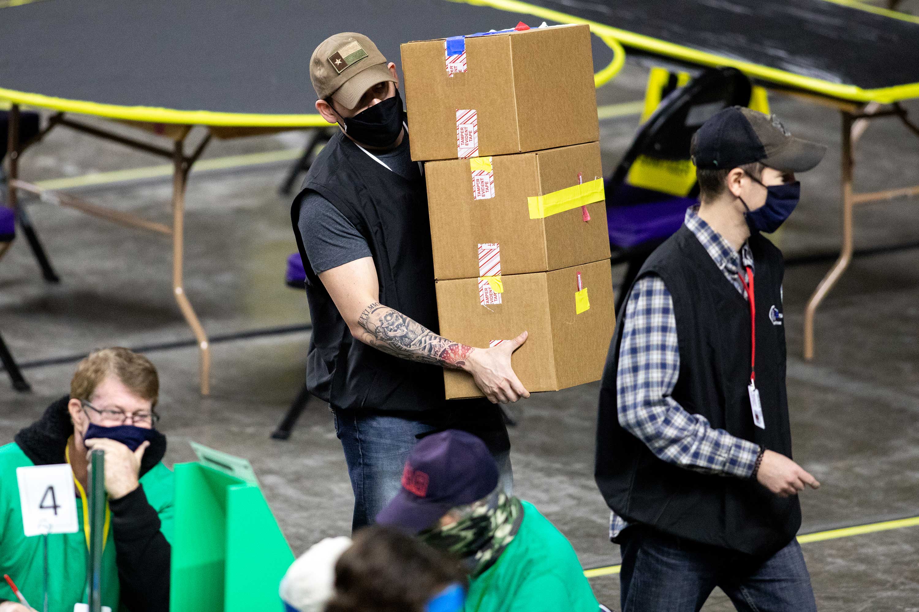 Election workers carry sealed ballot boxes at a counting center; federal memos say more than 600,000 Maricopa County voter records were taken in the 2020 incident.