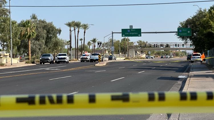 Police tape and patrol vehicles block a Phoenix roadway as officers secure the scene near downtown following a reported single-vehicle rollover crash.