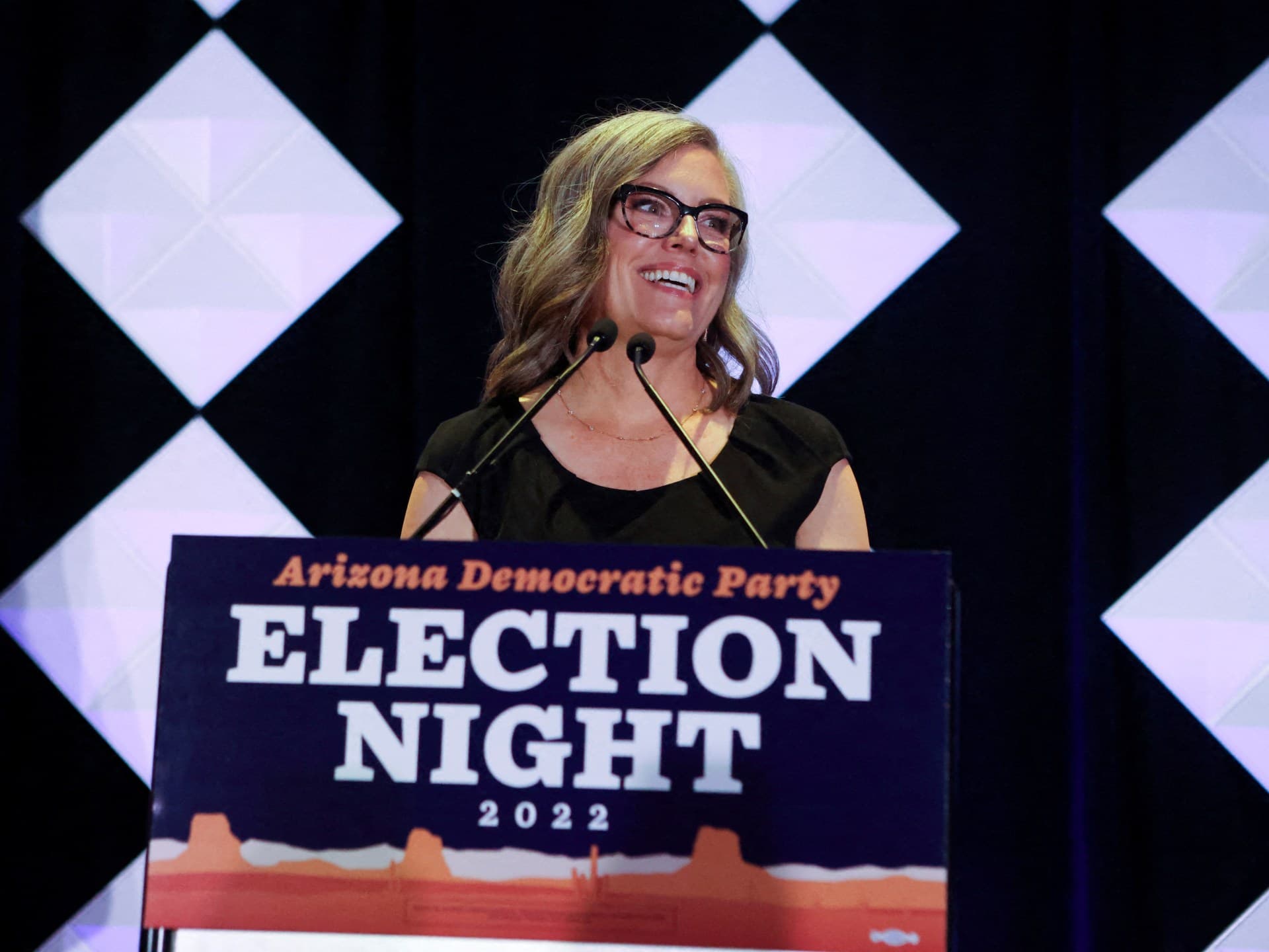 A woman speaking behind a lectern reading 'Election Night 2022' at a party event — usable for reporting on the ongoing investigation into Arizona’s governor as voters head to the polls.