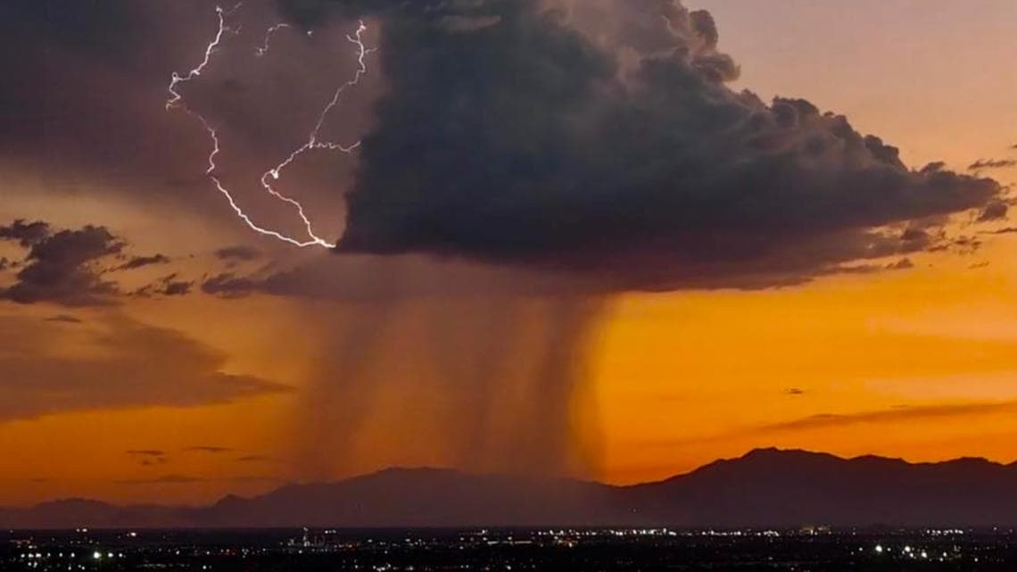 A storm cell produces a concentrated rain shaft and lightning over the valley at sunset, one of the severe cells tied to widespread damage reports and power outages in the West Valley.