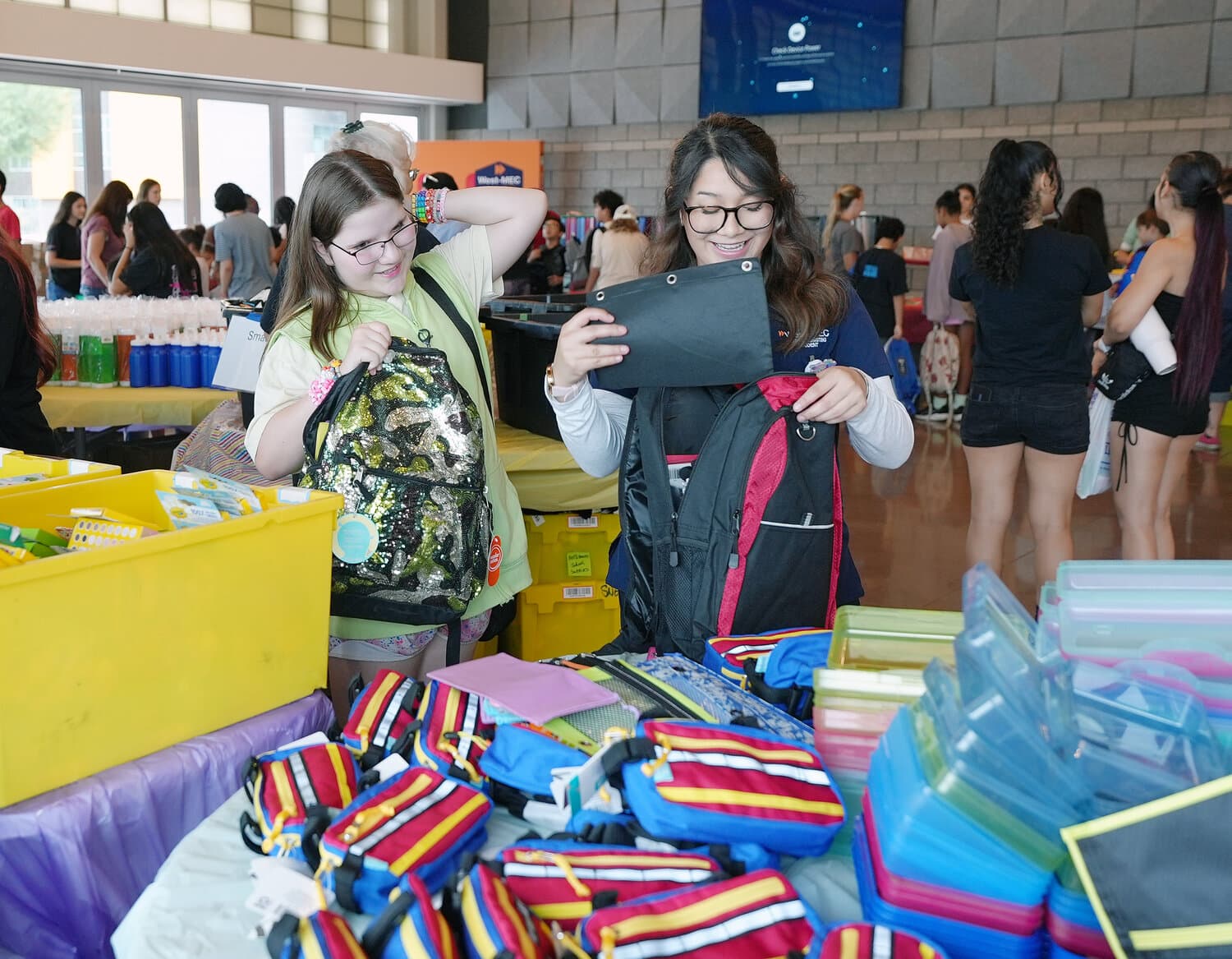 Children examine backpacks while volunteers hand out school supplies during a Valley back-to-school event where families received free items.