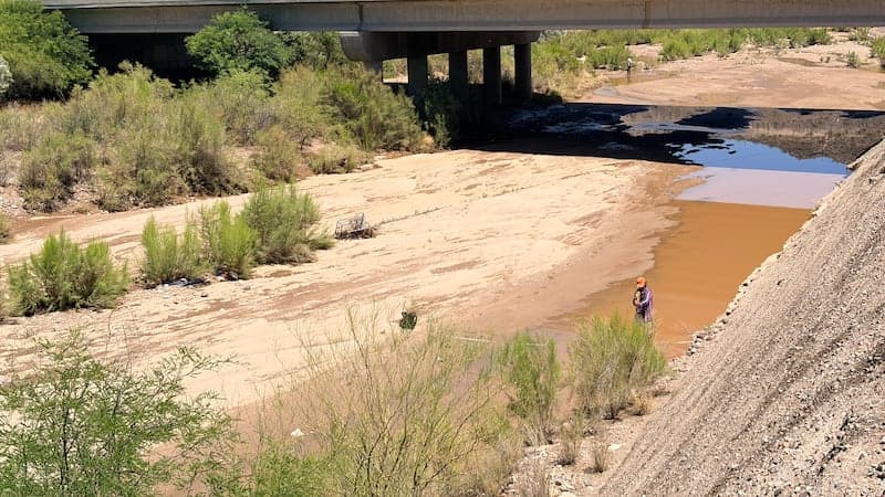 A largely dry riverbed beneath a highway bridge, illustrating low surface flows and the groundwater recharge challenges highlighted in the statewide water-supply study.