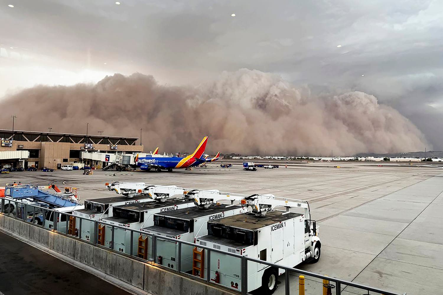 A massive wall of dust advances across Phoenix Sky Harbor International Airport as Southwest jets sit at the gates, illustrating the storm that disrupted flights and ground operations.