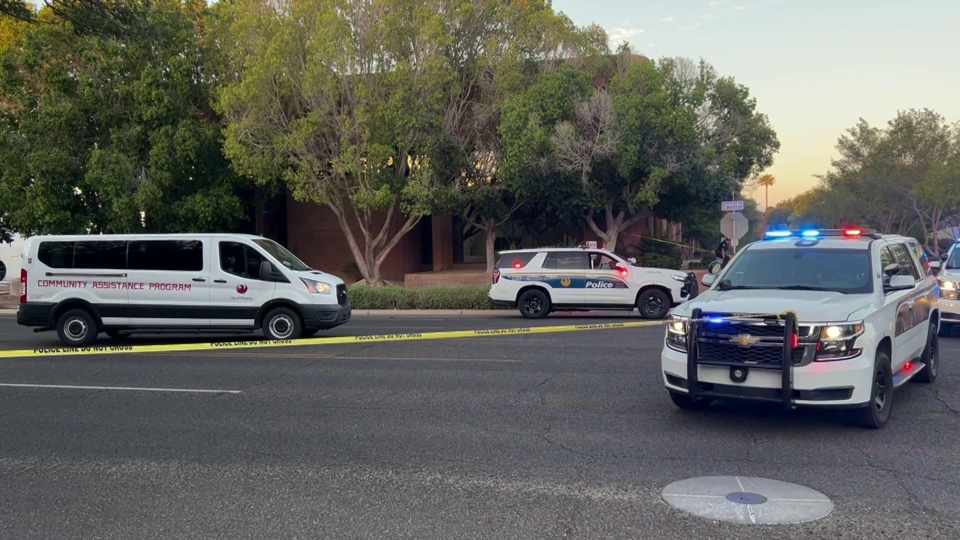Police vehicles and a Community Assistance Program van block off a stretch of road with yellow tape near Central and Missouri avenues in Phoenix after officers responded to a reported stabbing.