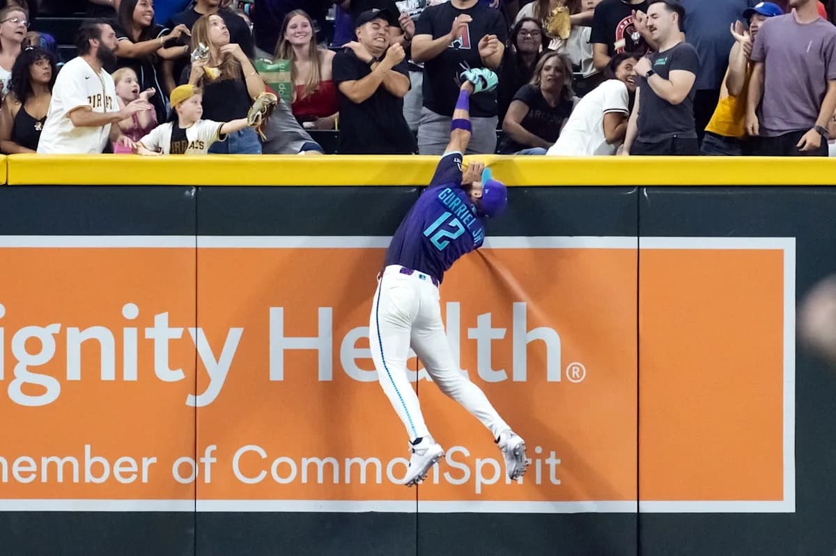 Arizona Diamondbacks outfielder leaps at the outfield wall to rob a would-be home run during the third inning at Chase Field on July 3, 2026, as fans react behind the fence.