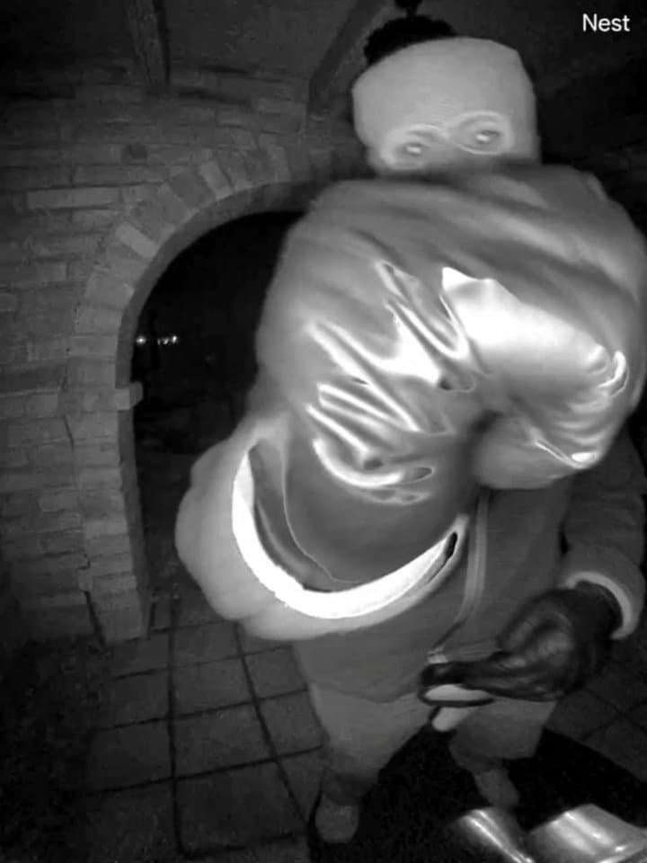 Night-vision doorbell still showing a masked figure at a front entryway; police say DNA recovered inside the home did not identify a suspect.