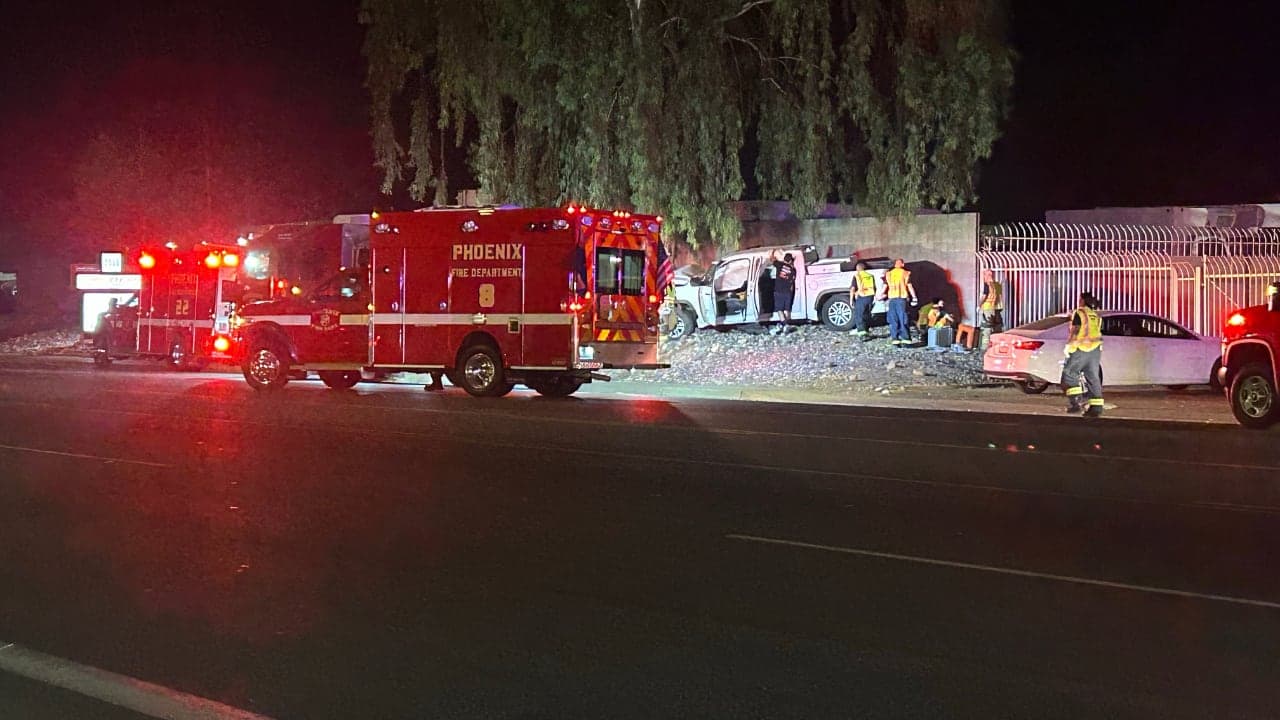 Phoenix Fire Department ambulance and first responders at the scene where a pickup struck a tree near 7th Street and University Drive; three people were critically injured and taken to hospital.