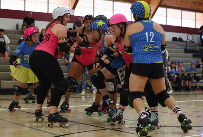 Skaters from two teams push through the pack during a roller derby game at the Broadway Recreation Center in Mesa, showing the close, physical play at the heart of Arizona’s derby scene.