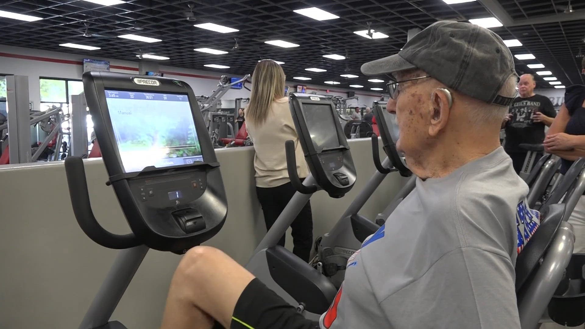 A 100-year-old Mesa resident pedals a recumbent exercise bike at a local gym as part of his birthday workout before cake.