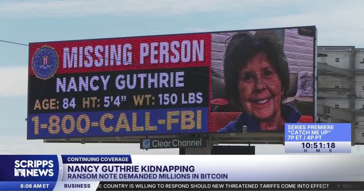 Roadside billboard displaying a missing‑person alert and an FBI tipline amid continuing news coverage of the ongoing investigation.