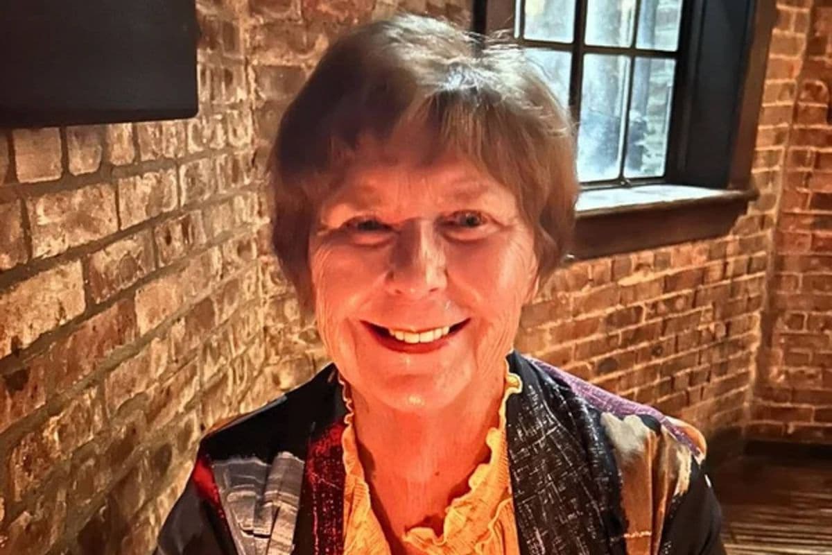 Portrait of an older woman seated against a brick wall; authorities are investigating an Arizona home invasion in the wider Nancy Guthrie case.